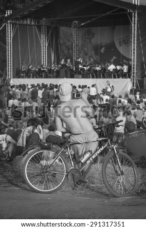 Krasnoyarsk, Russia - June 19, 2015:Man on a bicycle concert takes the audience on a mobile phone   Summer Youth Festival of symphonic music 