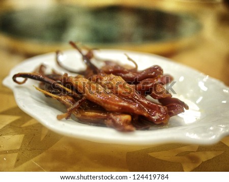 Roasted duck tongue sitting on porcelain serving dish at a Chinese banquet