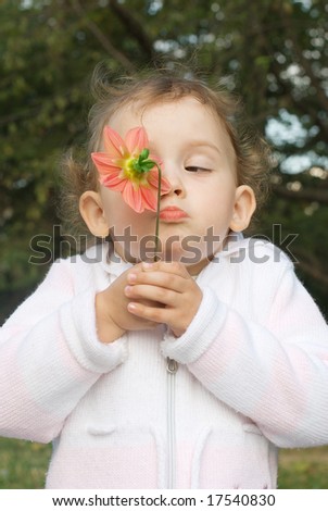 Surprised girl is smelling red flower