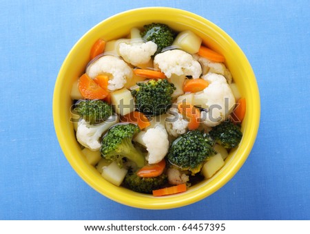Steamed vegetables with broth in yellow bowl.
