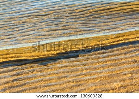 A small wave rolls gently into the sandy beach