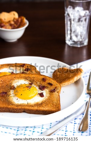 Egg fried in a heart-shaped toast cutout sprinkled with bacon crumbs, cracked pepper and thyme
