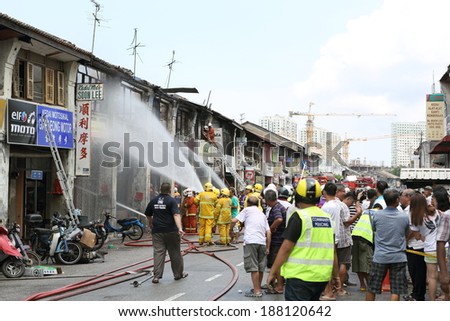 Georgetown Penang. Heritage Shop houses on Fire April 20th 2014. Firefighters on the scene tackling the blaze. Large crowd gathered to watch the fire crews in action.