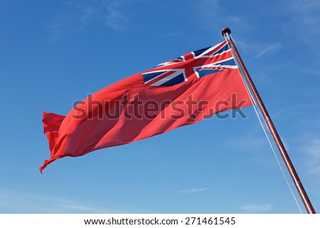 Flag of the British Merchant fleet the Red Ensign. Flag pole rising from bottom right with flag billowing to the left.