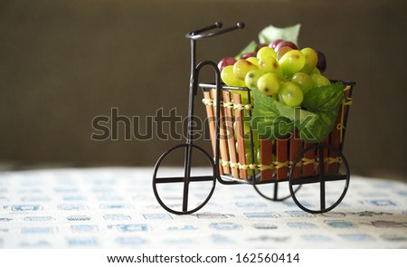 Violet and green Grapes in cute small bicycle