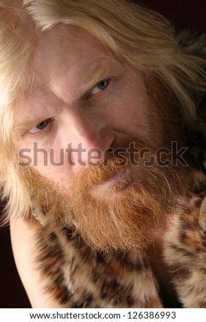 close-up portrait of an adult male with long hair, blonde, with a red beard and mustache, wearing a fur dress, looking in the direction of
