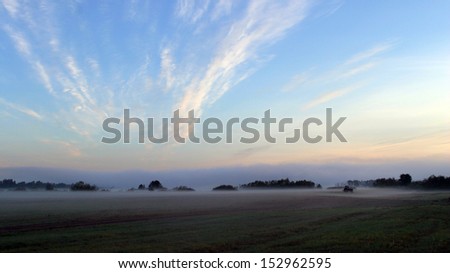 beautiful long bands of clouds in the blue sky in a field near the river in the early morning