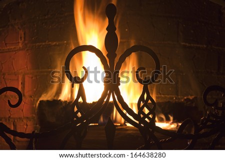 close up of a beautiful wrought-iron grate against the bright flame and a brick wall