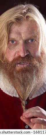 close-up portrait of an adult male with long blonde hair with a mustache and beard in medieval costume studio on a burgundy background