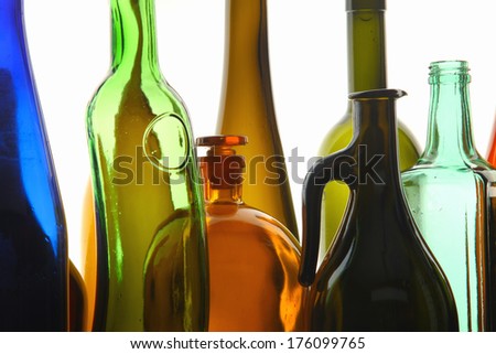 close-up clean transparent colored glass bottles of different shapes on the mirror surface in white light studio