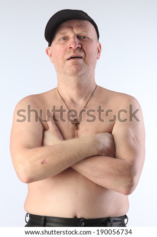close-up portrait of the adult white male with naked torso and a black baseball cap with a stern look studio