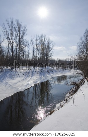 scenic landscape river trees without leaves on the shore and the melting of snow and ice in sunny day early spring