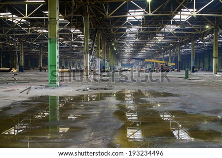 Abandoned plant interior with rusty metal equipment, wall and metal poles