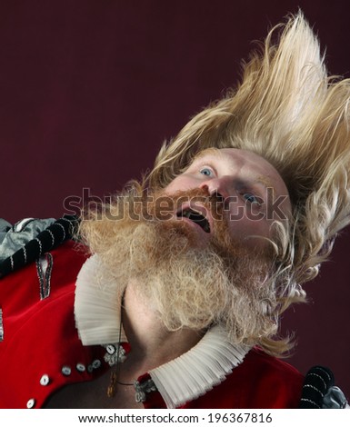 portrait of adult male with long hair beard and mustache in medieval costume tossing hair
