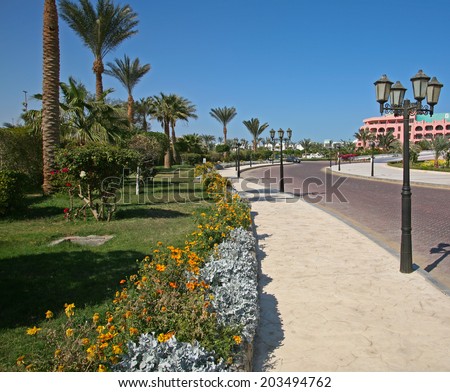 seaside resort hotel building and landscaped grounds with pool and flower beds on a hot sunny day