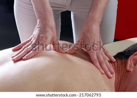 Isolated close-up of the hands of the masseur - female on man\'s back during a session, studio