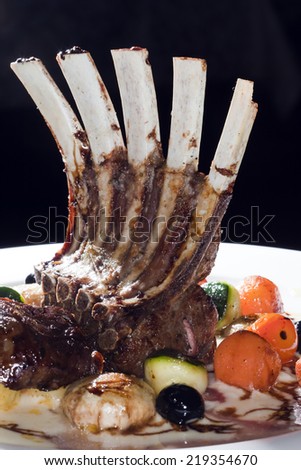 macro ribs with grilled vegetables on white plate on dark studio background