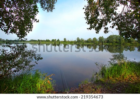 summer landscape glassy surface of a calm river and trees on the horizon in the early morning