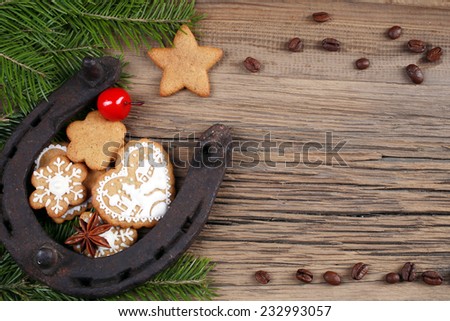 close-up still-life of fir branches, the horseshoes and gingerbread with pattern on magic Christmas holiday on background a wooden boards studio