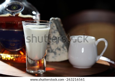 close-up of a still life with glass of warming drinks on the background bottles, jugs and a piece of cheese