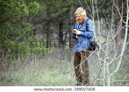 portrait photographer with a red beard and a mustache in a meadow in early spring
