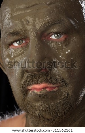 close-up bald man in a clay with ethnic pattern on the forehead on a black background Studio