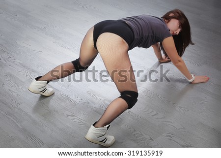 close-up sexy redhead girl showing sports buttocks on a background of gray flooring studio