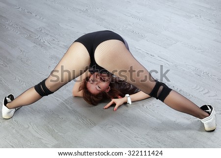 close-up sexy redhead girl showing sports buttocks on a background of gray flooring studio