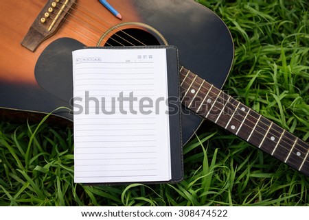 Paper for writing songs with a guitar on the lawn.