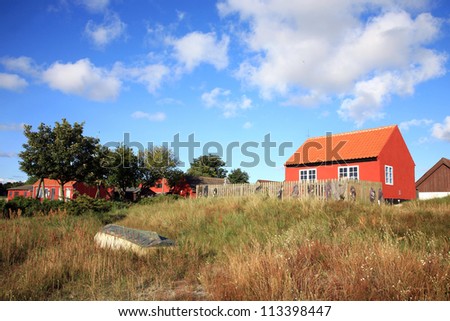 Typical red Scandinavian house on coastline in Snogebaek, early morning and wooden boat on dunes -  Bornholm, Denmark