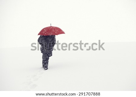 Man walking in winter snow storm in the snow next to the forest