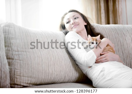 Attractive mixed asian woman hugging kitten on sofa