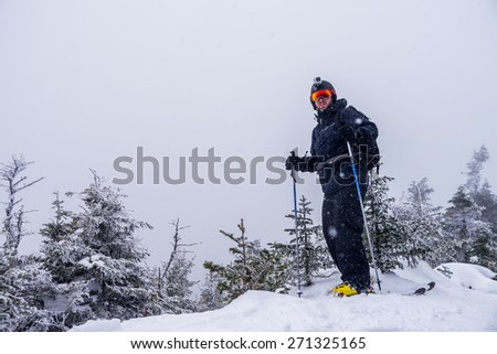 A skier stands on the summit of a mountain in a snow storm