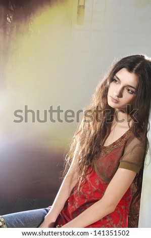 Portrait of young woman sitting cube in studio