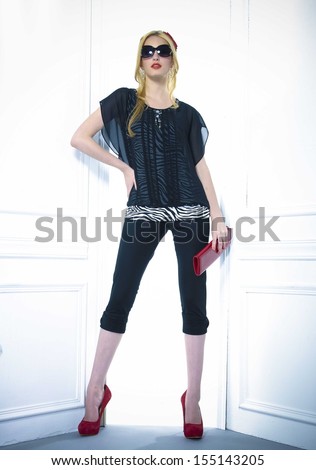 full-length portrait of young model in sunglasses with purse near door posing