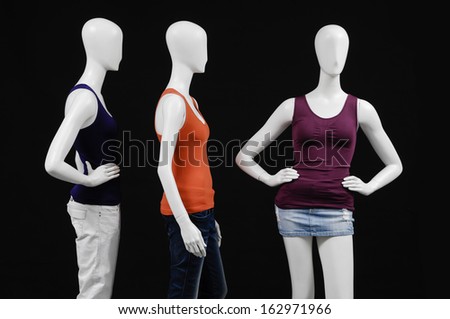 Three mannequin female dressed in red and black dress on black background