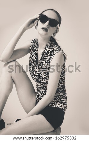 young woman in sunglasses sitting cube studio gray