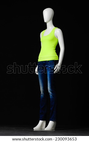 full-length female mannequin dressed in green dress and jeans on black background