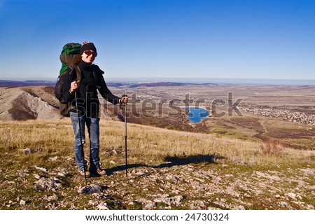 Hiker girl in sunglasses and with hiking poles on the mountain summit