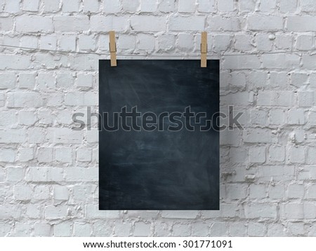 Blank blackboard hanging against a white brick wall
