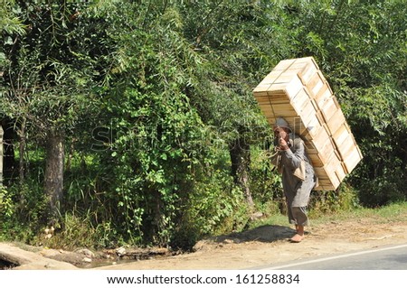 Pahalgam, Kashmir - 20 September: An old man carrying heavy boxes on his back containing apples in front of an apple orchard on September 20, 2011 in Pahalgam, Kashmir, India