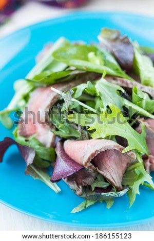 Green salad with grilled beef steak medium rare, mix lettuce, arugula, tasty fresh dish