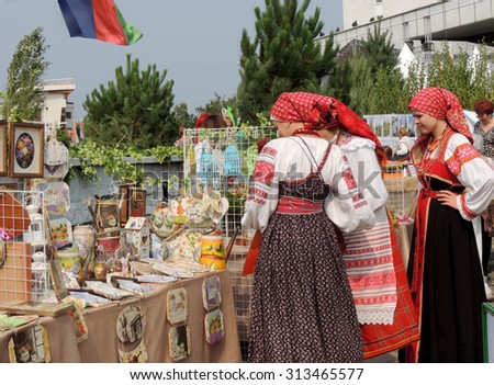 Voronezh, Russia -September 5, 2015: Young women in Byelorussian national costumes with embroidery near street stand of souvenirs on the city square during the exhibition-fair 