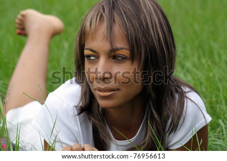 Close-up of a lovely mature black woman in a grassy field, looking off-camera toward frame left.