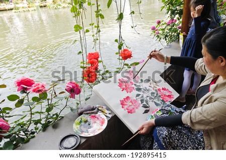Hangzhou - May 2: a painter painting Chinese rose seriously in the garden. On May 2, 2014 in hangzhou, China. Hangzhou is a leisure city.
