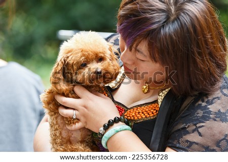 Hangzhou - September 21: hangzhou sports park, a woman holding a lovely brown Biti bear  dog, on September 21, 2014 in hangzhou.