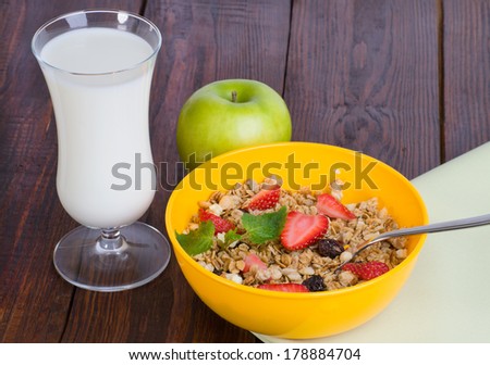 muesli with strawberries, apple and a glass of milk on wooden background
