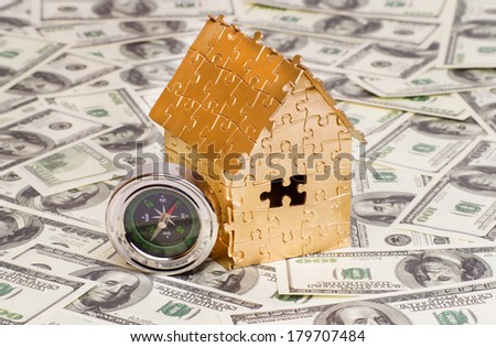 home gold color with compass on a background of 100 dollar bills. concept of home buying, mortgages, insurance