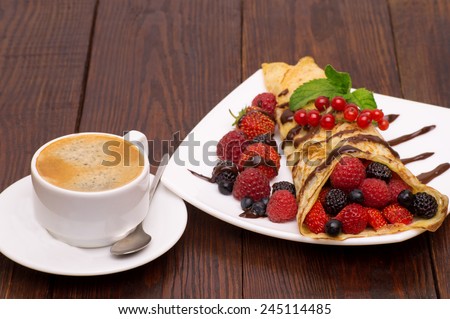 Crepes With Berries and cup of coffee .Crepe with Strawberry, Raspberry, Blueberry and Chocolate topping. Pancake