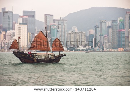 HONG KONG, CHINA - DECEMBER 8, 2012: a junk ship (traditional Chinese boat) sails along the harbor against the skyline. HK is a busy global metropolis of contrasts, where tradition meets modernity.